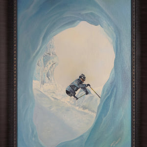 Framed painting of a skier in a snowy landscape viewed from inside a blue icy cave, enclosed in a dark wood frame.