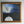 “Moonrise painting hanging on a light wall, with an angel and moon beneath a blue sky, surrounded by an ornate gold frame.”