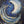 Artistic depiction of a crescent moon with swirling blue and gold patterns on a dark background.