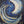 An abstract painting of a crescent moon and swirling waves in deep blue, white, and gold tones, with small gold star-like speckles across a dark navy background.