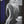 A dark, surreal painting of a seated nude figure with a long, curly white beard and hair, rendered in black, white, and gray tones against a background with a deep blue shape and a white moon-like circle.