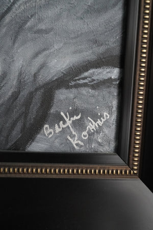 Close-up of a framed black and white painting with a visible signature reading 'Becki Korthuis' in white script, set in a dark frame with a gold-toned beaded inner border.