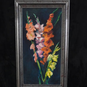 A framed vertical oil painting of gladiolus flowers in shades of orange, pink, and yellow against a dark background, housed in a distressed dark gray frame.