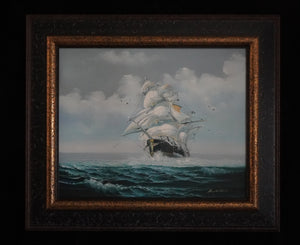 Where Courage Sails painting of a white-sailed ship on teal waves beneath cloudy skies, in a dark frame with gold trim.”
