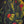 Close view of the Where the Garden Keeps Its Secrets painting showing red and golden-yellow flowers among lush green foliage on a dark background