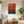 Lifestyle mockup of The Crimson Challenge abstract rooster painting hanging in a modern living room